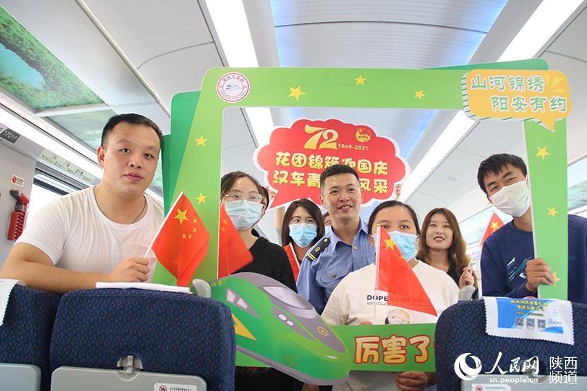 2021年9月30日，陽平關至安康跑起“復興號”動車組，標志秦巴深處的陽安鐵路全線邁入動車新時代。圖為陽平關至安康“復興號”動車上，西鐵漢中車務段團員青年志愿者與車上乘客。全超雷攝