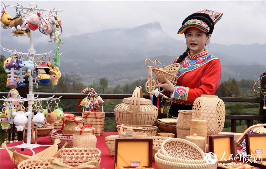 寧強(qiáng)縣羌編公司馮麗通過鏡頭向游客介紹寧強(qiáng)羌族手工業(yè)編制品。黎德華攝
