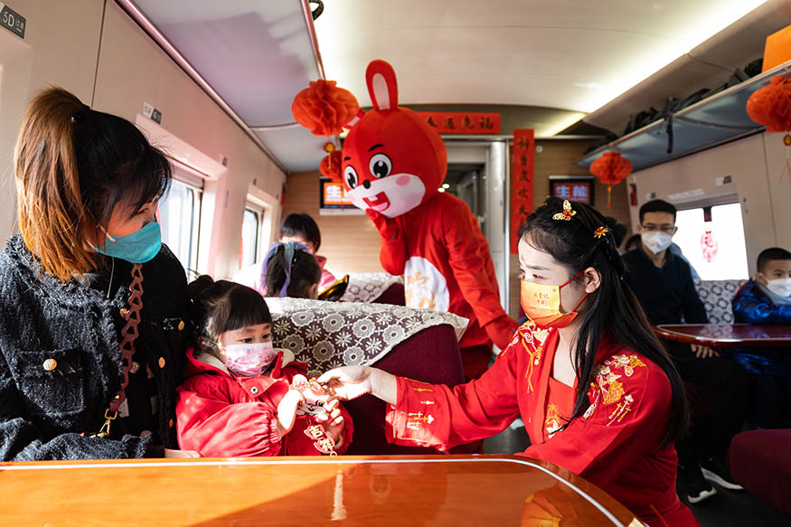 西安北至深圳北G824次列車，高鐵乘務(wù)員裝扮成“嫦娥”為小旅客贈送兔年主題掛飾。劉翔 攝