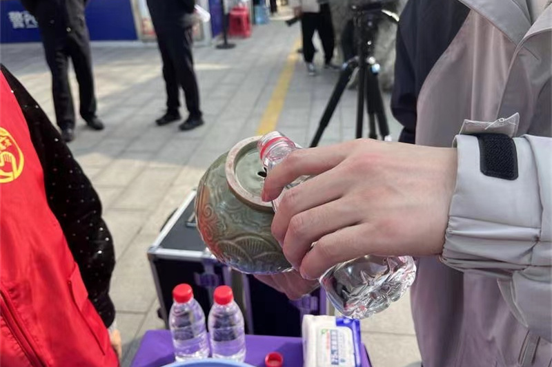 市民正在體驗(yàn)青釉提梁倒注壺（復(fù)制品）的物理原理。王瑛 攝
