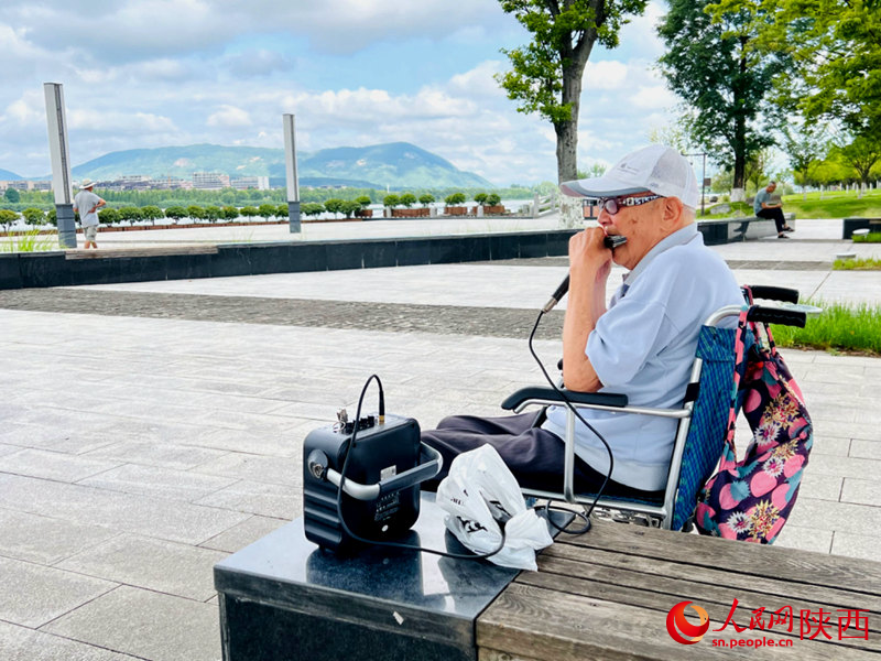 94歲的張大爺每天都會(huì)到天漢濕地公園憩息吹口琴。人民網(wǎng)記者 孫挺攝