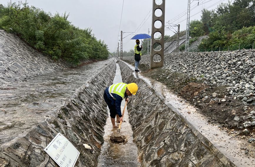 漢中工務段西鄉(xiāng)線路車間防洪人員在陽安線西鄉(xiāng)至沙河坎區(qū)間清理水溝。金嶸攝