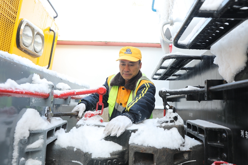 西安鐵路局寶雞供電段秦嶺供電車間接觸網(wǎng)軌道作業(yè)車司機(jī)正在清理車輛連接處積雪。張贏弘 攝