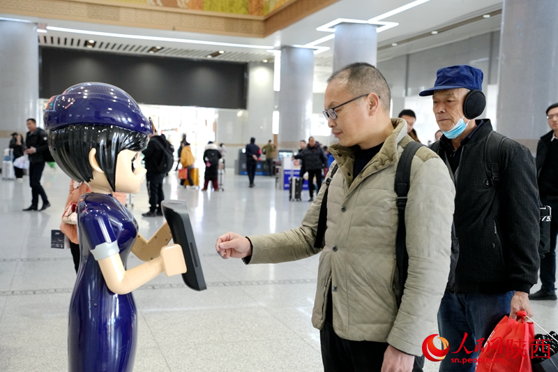 旅客向智能AI問詢機(jī)器人詢問車票信息。人民網(wǎng)記者 鄧楠攝