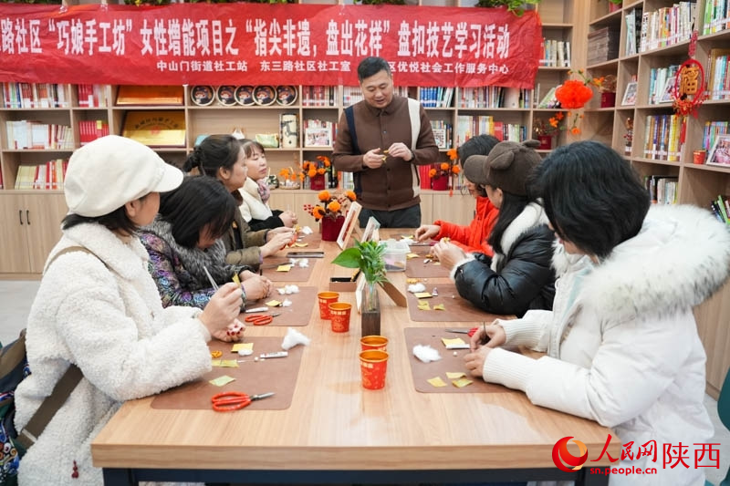 馬海濱強(qiáng)調(diào)“四葉草”盤(pán)扣的制作要點(diǎn)。人民網(wǎng)記者 李志強(qiáng)攝