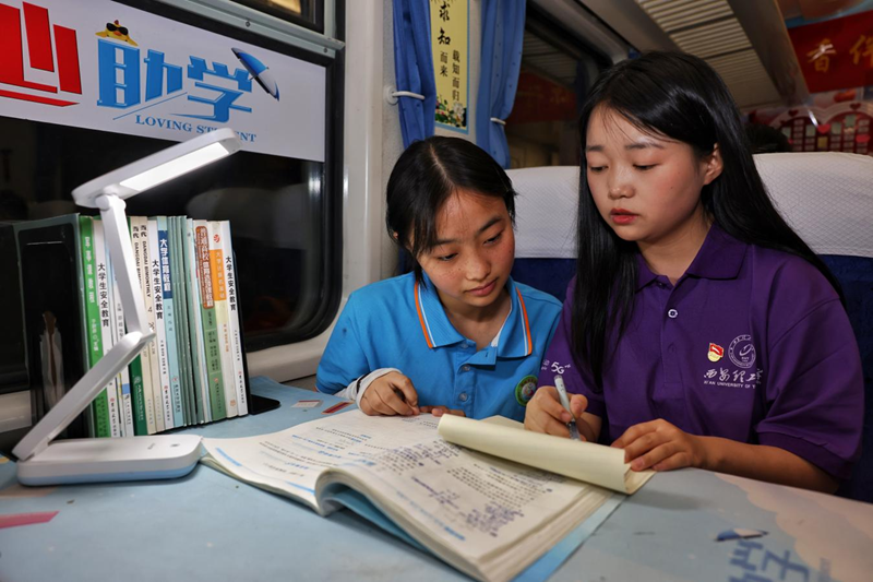 西安理工大學(xué)的志愿者給乘車(chē)孩子們講解習(xí)題。劉松霖?cái)z