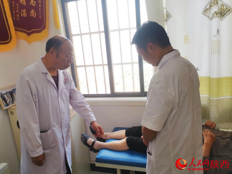 劉永生正在指導(dǎo)兒子劉博診斷患者病情。人民網(wǎng) 王麗攝