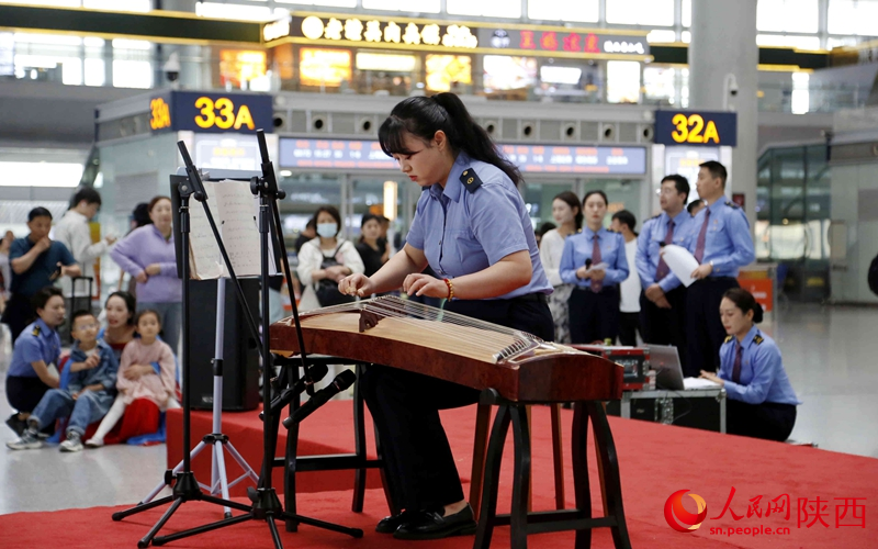 西安北站工作人員現(xiàn)場彈奏古箏。人民網(wǎng)記者 賈凱璐攝