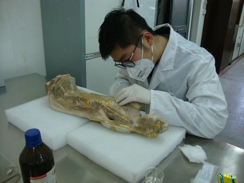 徐諾正在修復(fù)一件漢白玉彩繪貼金的文物。受訪者供圖