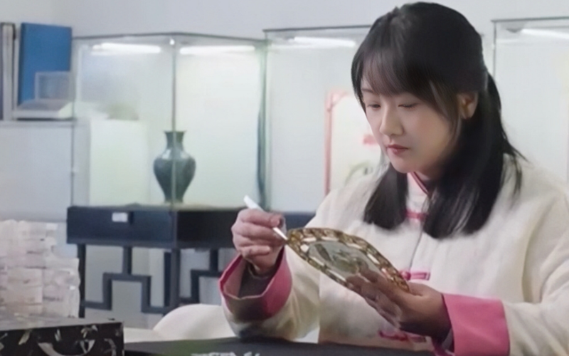 趙琳靜正在根據(jù)文物原樣復(fù)刻一把文創(chuàng)扇子。受訪者供圖