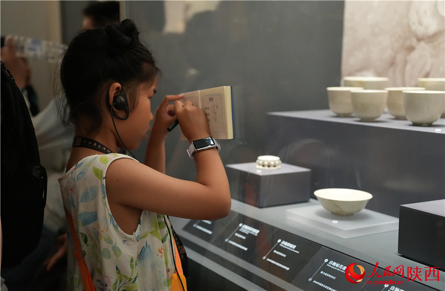 一名小學(xué)生在陜西考古博物館的文物展柜前做記錄。人民網(wǎng)記者 李志強(qiáng)攝
