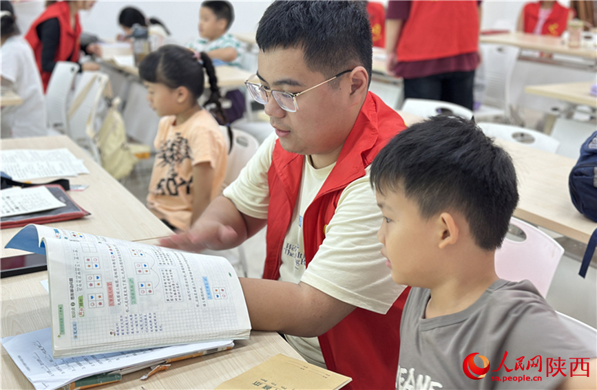 7月16日，西安市新城區(qū)明宮社區(qū)的志愿者在給孩子輔導(dǎo)作業(yè)。人民網(wǎng)記者 李志強攝