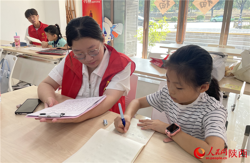 7月16日，西安市新城區(qū)明宮社區(qū)的志愿者在給孩子輔導(dǎo)作業(yè)。人民網(wǎng)記者 李志強(qiáng)攝