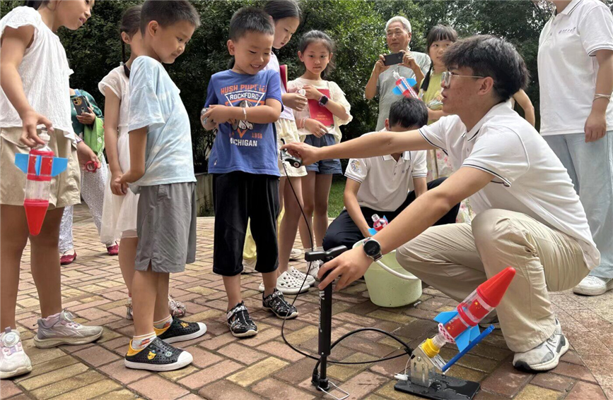 7月8日，高校志愿者在西安市雁塔區(qū)杜城街道金地西灃公元社區(qū)指導孩子們制作水火箭。杜城街道辦供圖