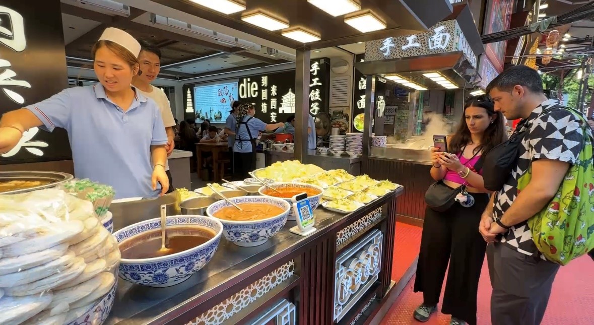 回民街里，外國游客對肉夾饃很感興趣。人民網(wǎng)記者 白鴿攝