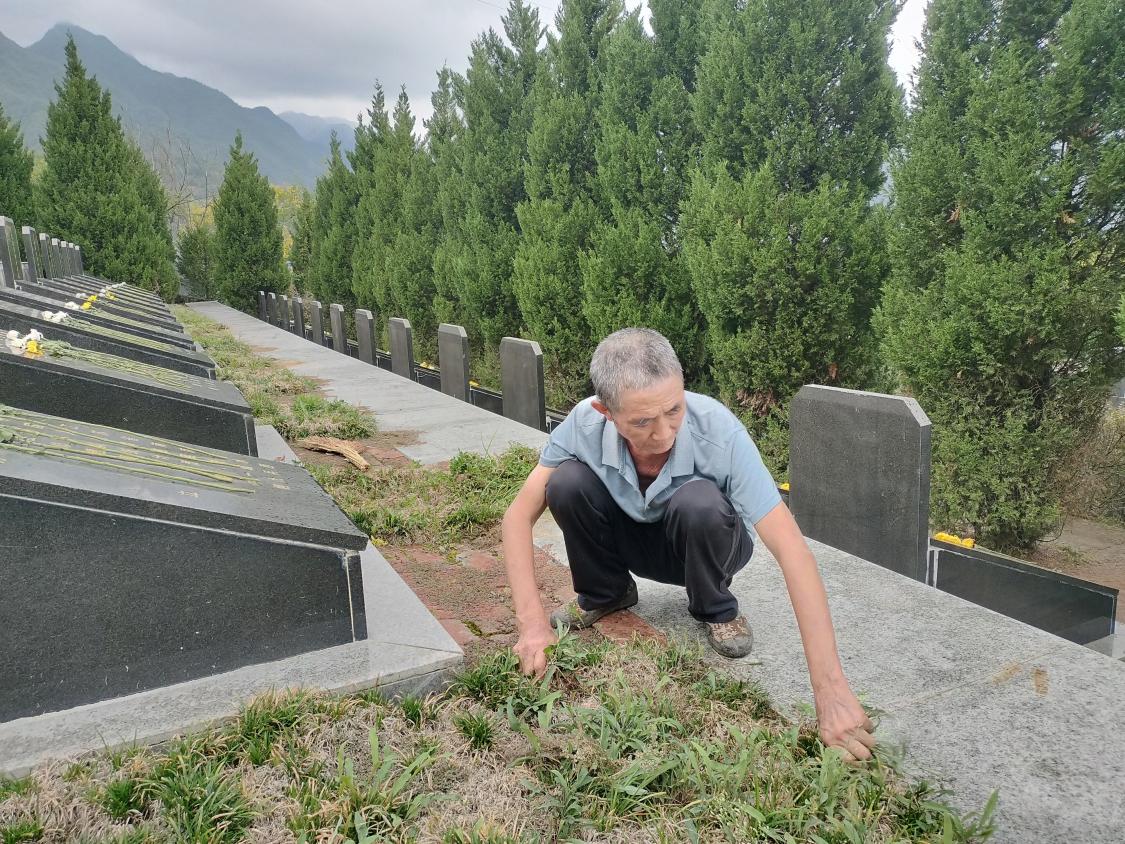 王開茂在烈士墓前除草。張開朝攝
