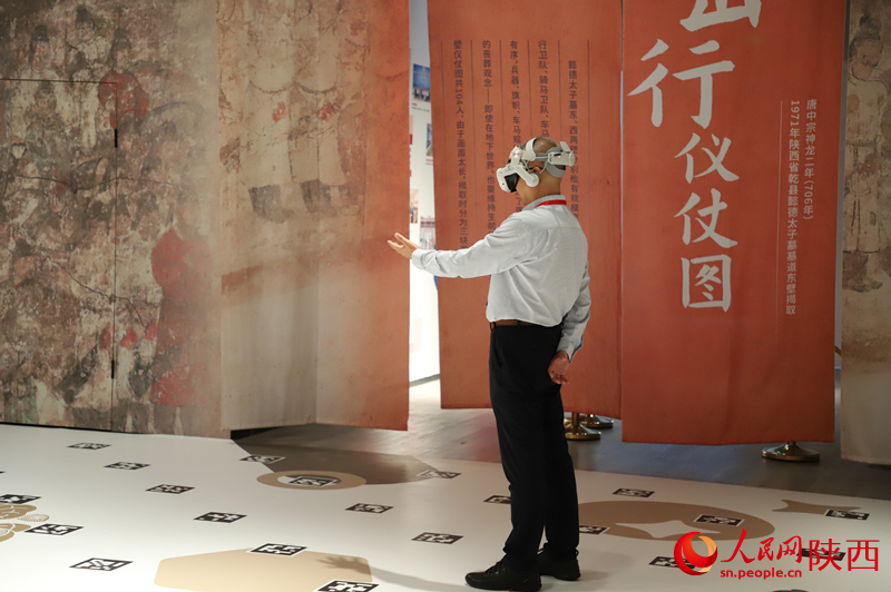 一名《壁畫那邊是唐朝》項(xiàng)目的體驗(yàn)者正在和劇情互動(dòng)。人民網(wǎng)記者 李志強(qiáng)攝