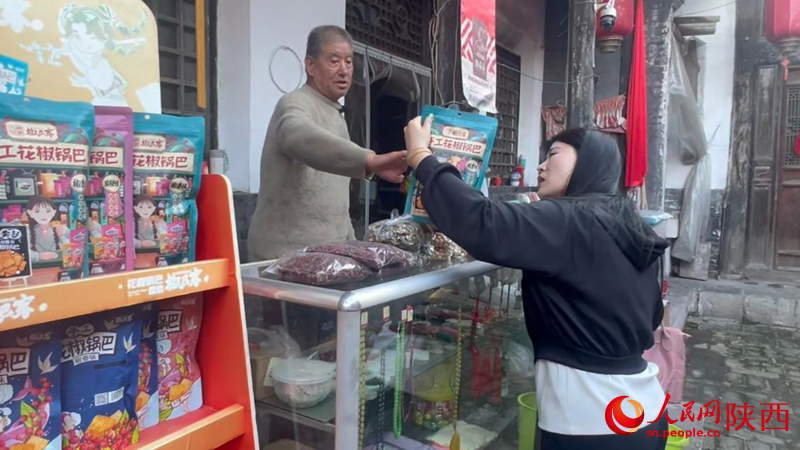 黨大爺向游客推薦當(dāng)?shù)靥禺a(chǎn)。人民網(wǎng)記者 白鴿攝