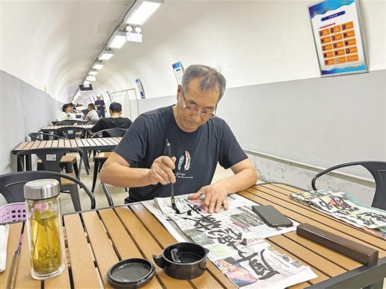 8月7日，一位老人在西安人防納涼中心乘涼、寫字。記者 周明攝